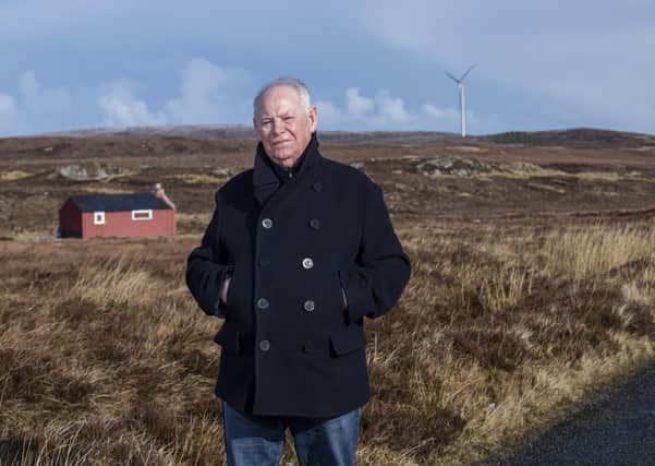 Calum Graham near his family’s old airidh, with the Point and Sandwick Trust turbines at Beinn Ghrideag in the background. Picture by Sandie Maciver of SandiePhotos
