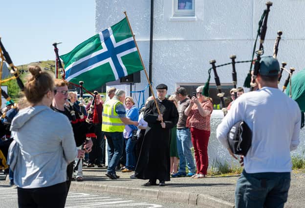 Father Ross Crichton leads the protest with the South Uist flag. (Pic: Seonaidh MacInnes)
