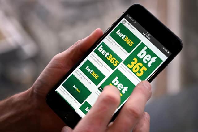 A man poses for a photograph with the logo for online gambling website Bet365 displayed on a smartphone, in London on December 18, 2019. - Denise Coates, chief executive of British online betting giant Bet365, has retained her place as Britain's highest-paid boss, according to the group's annual report published on Wednesday. She was paid a basic salary of £277 million ($366 million, 328 million euros) in the group's financial year to March, the company's annual report showed. (Photo by PAUL ELLIS / AFP) (Photo by PAUL ELLIS/AFP via Getty Images) : Gambling is now ubiquitous in society and available 24 hours a day through modern technology, with little restriction.