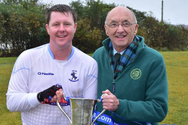 Captain David Grant is presented with this years Mod Shinty cup by John Macleod, President of An Comunn Gaidhealach . David led Skye to a 3-0 win over Lewis in tough conditions in Shawbost.