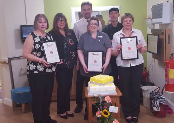 Manager Peter Venus and Area Manager Jackie Macdonald pictured with the staff who received long-service certificates and the special anniversary cake.
