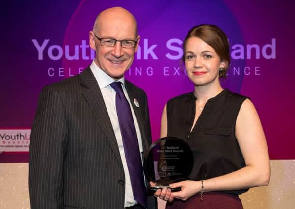Deputy First Minister John Swinney presents Girlguiding Scotland volunteer Matilda Lomas with her award.