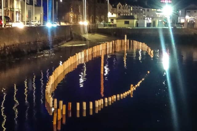 The installation lit up at night, as the tide comes in to consume it.
