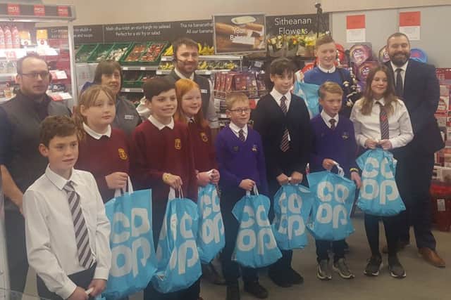 The kids from Stornoway and Laxdale Primary Schools, get some goodie bags as a thank you for their ribbon cutting duties, from the Co-op management team at the new store.